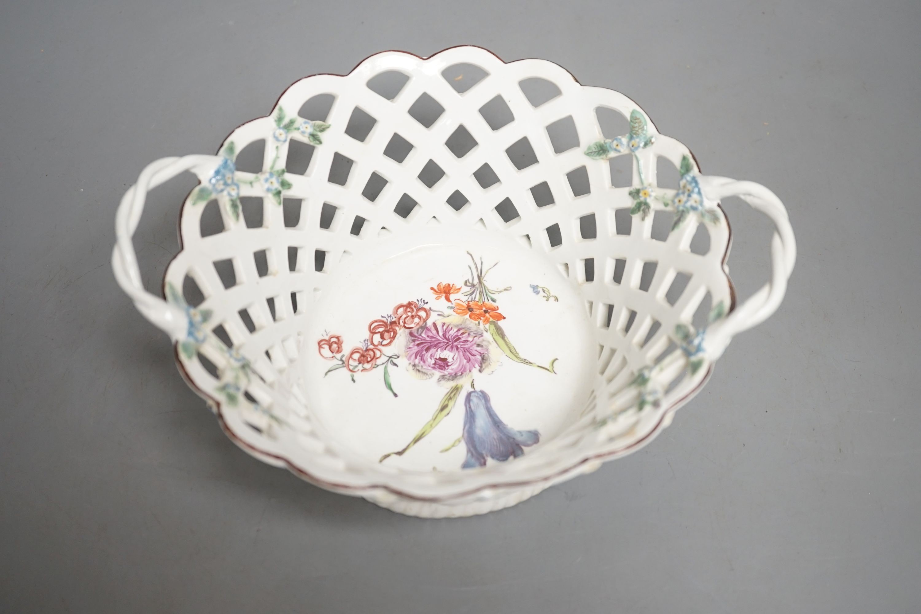 A Chelsea pierced two handled basket the centre painted a large floral bouquet, the handles with applied as is the exterior of the back, red anchor and stilt marks c. 1755, 20cm across